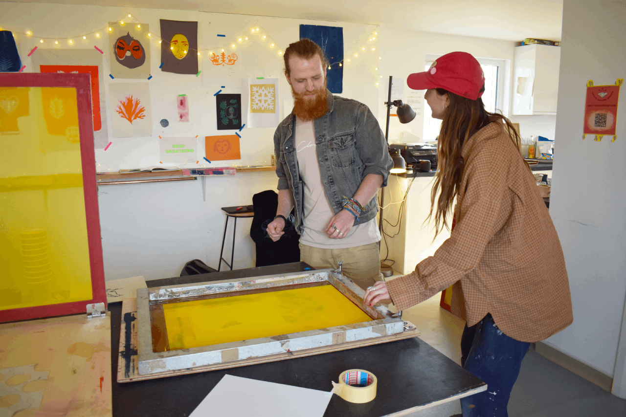 workshop host Madeline Rolt teaching a man to screen print in an art session at The Pearl Exchange