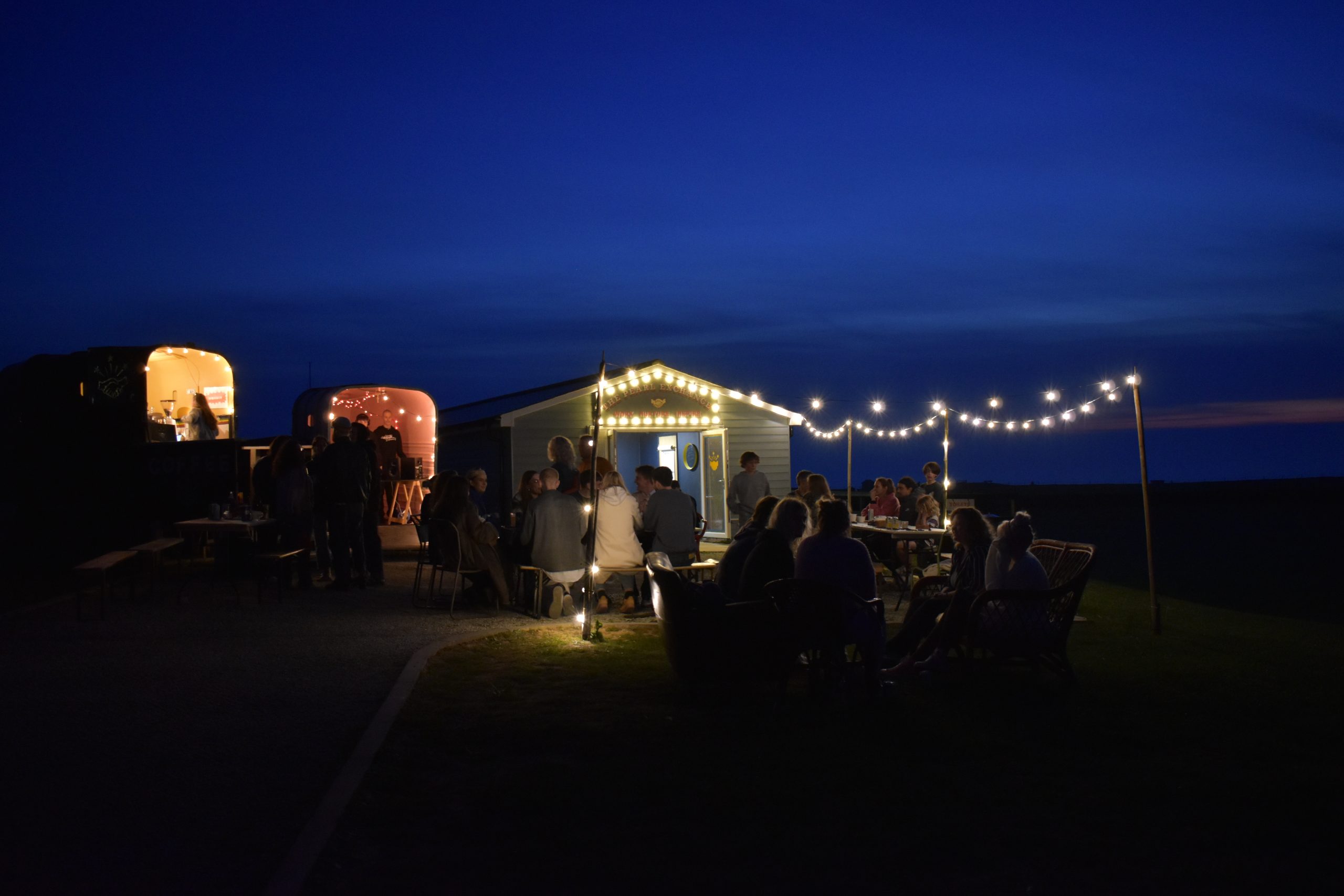 a photo of the outdoor space at the Pearl Exchange with fairy lights, a DJ booth, the Horsebox cafe serving drinks and lots of people sitting and chatting